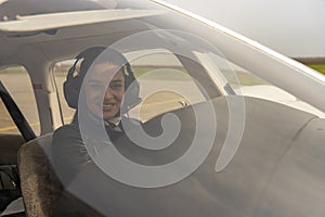 Smiling Young Woman Pilot With Headset Looking Through The Cockpit Window