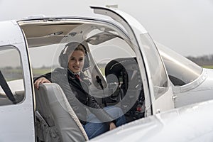 Smiling Young Woman Pilot With Headset Sitting in Cockpit of Private Aircraft