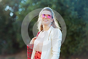 smiling young woman in pink dress and white jacket in city