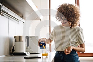 Smiling young woman pouring juice into the glass