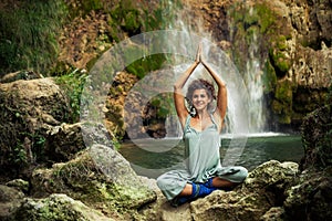 Smiling young woman practice yoga outdoor on the rocks by the wa