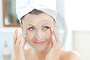 Smiling young woman putting moisturizer