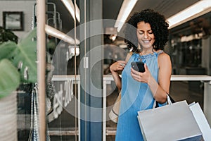 Smiling young woman reading a cellphone text while out shopping photo