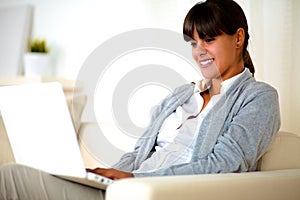 Smiling young woman reading the laptop screen