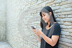 Smiling young woman reading text message or social media on cell telephone