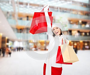 Smiling young woman with red shopping bags