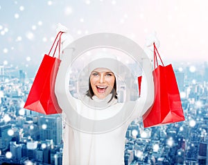 Smiling young woman with red shopping bags