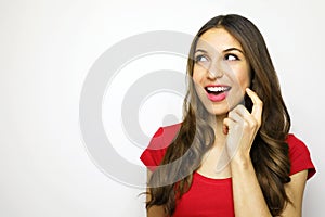 Smiling young woman with red t-shirt looking to the side desiring some thing on white background. Copy space. photo
