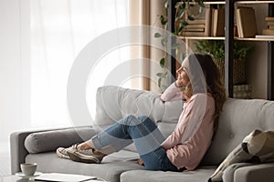 Smiling young woman relax on sofa dreaming