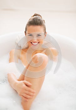 Smiling young woman relaxing in bathtub