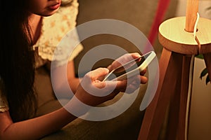 Smiling young woman relaxing on couch at home texting messaging, browsing wireless internet on smartphone