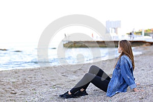 Smiling young woman rests on beach and poses in camera, sitting
