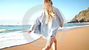 Smiling young woman running on sandy sea beach on summer vacation