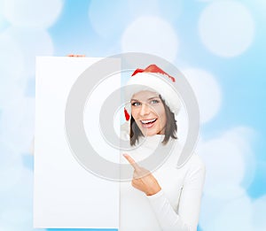 Smiling young woman in santa hat with white board