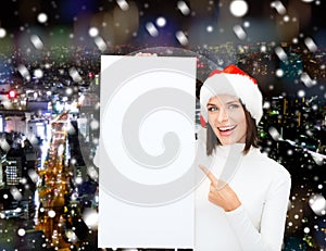 Smiling young woman in santa hat with white board