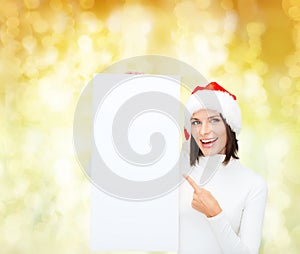 Smiling young woman in santa hat with white board