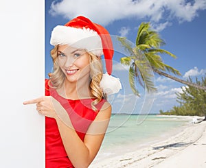 Smiling young woman in santa hat with white board