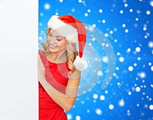 Smiling young woman in santa hat with white board