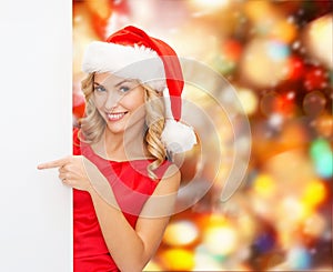 Smiling young woman in santa hat with white board