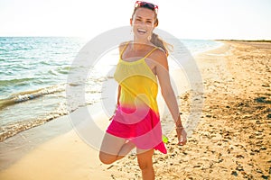 Smiling young woman on seacoast in evening having fun time