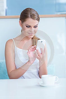 Smiling young woman sending an sms