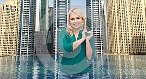 Smiling young woman in shirt showing heart shape