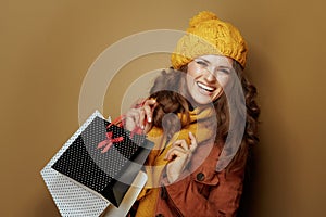 Smiling young woman with shopping bags against brown background