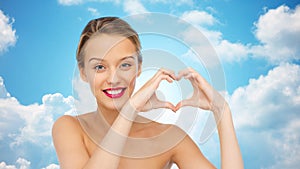 Smiling young woman showing heart shape hand sign