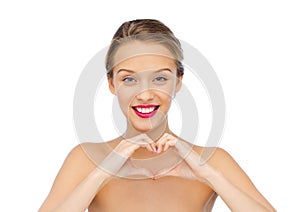 Smiling young woman showing heart shape hand sign