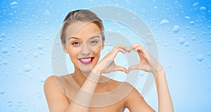 Smiling young woman showing heart shape hand sign