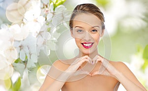 Smiling young woman showing heart shape hand sign