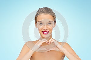 Smiling young woman showing heart shape hand sign