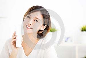 Smiling young woman showing skincare products