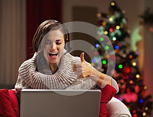 Smiling young woman showing thumbs up while having video chat