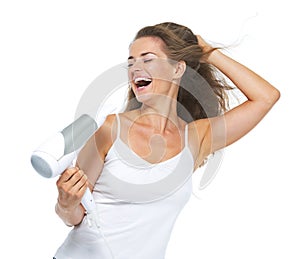 Smiling young woman singing while blow-dry