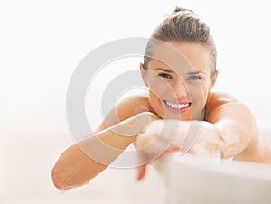 Smiling young woman sitting in bathtub