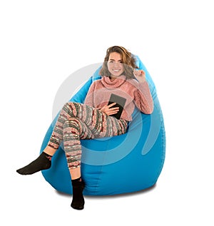 Smiling young woman sitting on blue beanbag chair and holding a