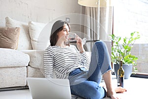 Smiling young woman sitting on floor with laptop computer.