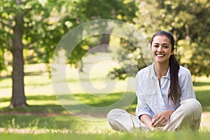 Smiling young woman sitting on grass in park