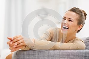 Smiling young woman sitting on sofa