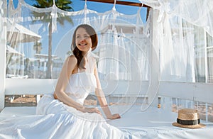 Smiling young woman sitting under white baldachin photo