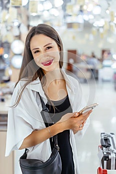 Smiling young woman with smartphone in supermarket