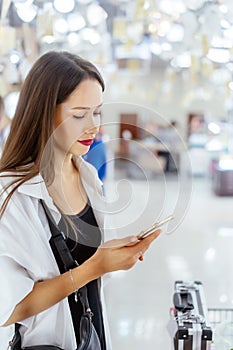Smiling young woman with smartphone in supermarket