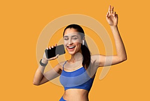 Smiling Young Woman In Sportswear Singing Holding Cellphone