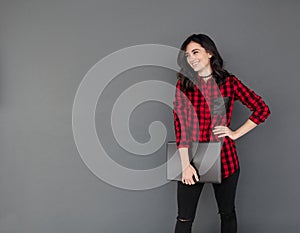 Smiling young woman standing and holding laptop