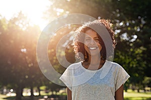 Smiling young woman standing in a park in the summer