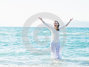 Smiling young woman standing in sea and sprinkling water