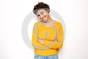 Smiling young woman standing by white background with arms crossed