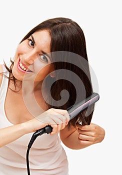 Smiling young woman straightening her hair