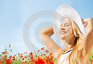 Smiling young woman in straw hat on poppy field